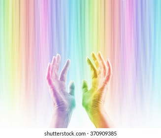 Absorbing Color Light Therapy - Female hands reaching up into rainbow colored light streaming down causing hands to become rainbow colored whilst absorbing the colored light