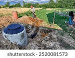 An absorption trench with perforated drainage pipe wrapped in geotextile is filled with soil using bayonet shovel.