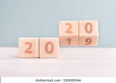 Abstract 2020 & 2019 New year countdown design concept - wood blocks cubes on wooden table and low saturation green background, close up, copy space.