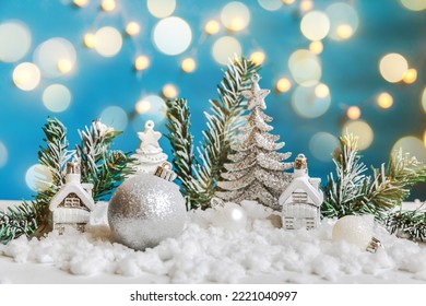 Abstract Advent Christmas Background. Winter decorations ornaments toys and balls on blue background with snow and defocused garland lights. Merry Christmas time concept