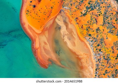 Abstract aerial view of blue-green water in shifting red deposition of sediment gradually moving through alluvial plains of Francois Peron National Park and surround area in Western Australia. - Powered by Shutterstock