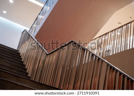 Abstract, angular view of a modern indoor staircase featuring copper-toned metal railings and dramatic lighting contrast