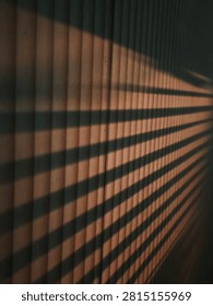 Abstract architectural background featuring dramatic light and shadow play from window shutters on vertical wooden panels.