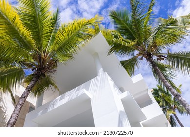 Abstract architectural background with white concrete house exterior fragment and palm trees under blue cloudy sky 
