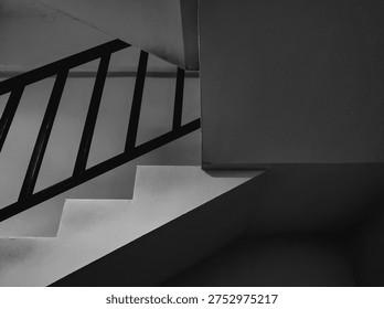 Abstract architectural composition featuring a tilted view of modern stairs and railings. This black and white photography emphasizes diagonal lines, repeating patterns, and dramatic shadows for a contemporary artistic look.