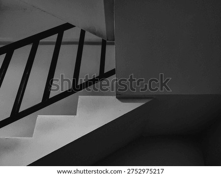 Abstract architectural composition featuring a tilted view of modern stairs and railings. This black and white photography emphasizes diagonal lines, repeating patterns, and dramatic shadows for a contemporary artistic look.