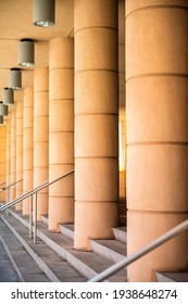 Abstract architectural row of columns pattern with hanging modern lamps lights and steps stairs staircase railing in vertical view
