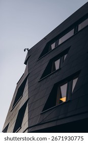 Abstract architectural view of a dark, angular building facade, emphasizing a minimalist and contemporary design.