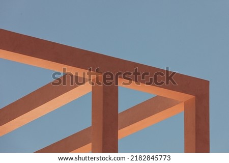Abstract architecture detail for background. Closeup of a geometric structure of dark yellow and orange concrete beam fragments against a blue sky. Shapes, forms of crossing cement bars for wallpaper.
