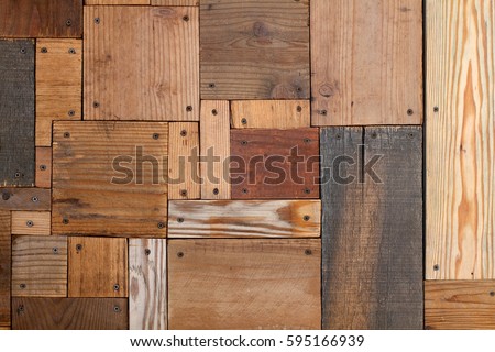 Abstract art background of varied weathered plywood and plank board rectangles and squares nested to from smooth surface of aged yellow and orange wood grains dotted with black screws in corners 