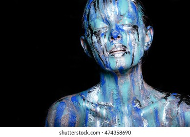 abstract art makeup. Face, neck and hair girls smeared with bright colors of blue, blue and silver colors. The paint flows. On the face of silver tears. Holi festival