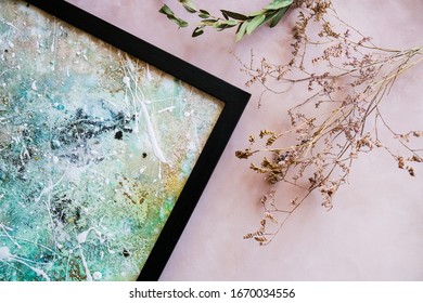 Abstract artwork in black frame and dried flowers. Top view. Stylish picture frame. Home decor concept.