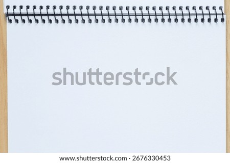 abstract backdrop: close up of blank page of sketchbook with spiral binder laying on table