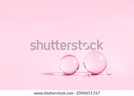 Abstract backdrop with glass spheres on pink pastel color background with sun reflections, monochrome 