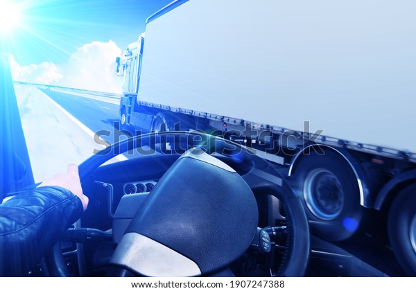 Abstract\
background with a black truck steering wheel and a truck with a\
trailer on a road against a sky with blue\
light