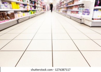 Abstract Background Blurred Photograph Of An Aisle With Shelves In Bright Modern Drugstore At Supermarket Shopping Center.