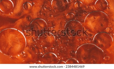 Abstract background. Bubbles liquid. Oily surface. Transparent drop circles moving spreading in bright orange shimmering glitter water in creative captivating art.