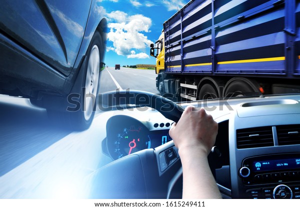 Abstract background with a close-up of a black\
car, car steering wheel and a truck with container against a sky\
with blue lights