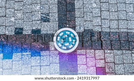 Abstract background with cobbled street tiles and LED lamp. Wallpaper of pavement with color pink blue toning. Cross. Geometric urban scene. Soft focus. film grain pixel texture. Defocused.
