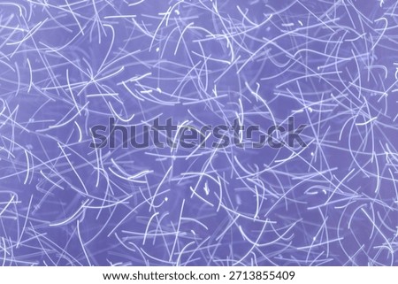 An abstract background created using light painting technique showcases a chaotic tangle of thin white light trails on a soft pastel purple backdrop. These random, wavy streaks convey a sense of motio