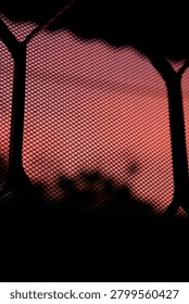 Abstract background featuring a bright, warm-colored sunset filtered through a geometric wire mesh window screen