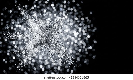 Abstract background featuring an explosion of silver glitter particles with sparkling bokeh light effects on a deep black backdrop. Dynamic festive texture with elegant blurred light spots and generous copy space for commercial design.