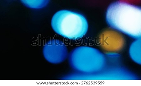 Abstract background featuring out of focus bokeh lights in vibrant blue and yellow hues against a dark black backdrop.