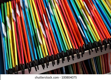 Abstract background image of colorful hanging file folders in drawer.  Macro with with extremely shallow dof.  Selective focus in front edges of files.