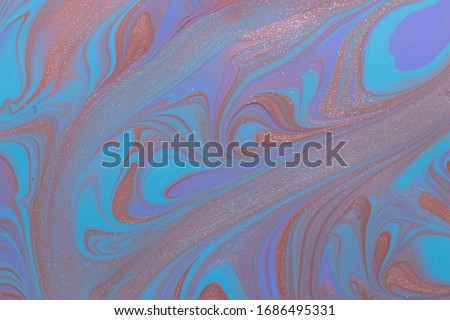 Abstract background of mixed shades of nail polish with a marble pattern and a shimmer. Creative watercolor blue, violet and bronze liquid colorful paint background