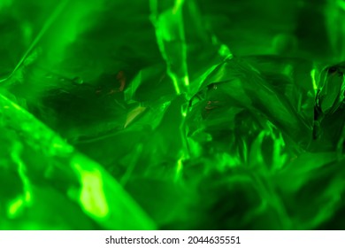 abstract background. neon green. macro photo of crumpled plastic bag with green light. appears radioactive or gemstone