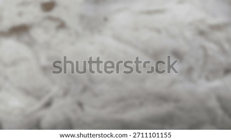 Abstract background out of focus, Macro background showing the rough fibers of off-white raw cotton (Gossypium hirsutum), displaying texture detail and small natural dirt particles.