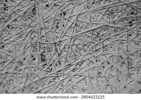 Abstract background of scratched texture with messy crisscross lines, weathered fiberglass surface in black and white monochrome