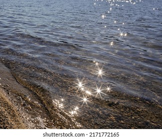 Abstract background of the sea or lake waves with sunbeams on the surface. Morning sunlight with sunbeams on a lake, nobody, copyspace for text, travel photo