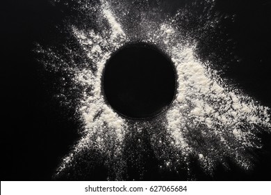 Abstract background. Sprinkled wheat flour circle, round spot on black. Top view on blackboard. Baking concept, cooking dough or pastry. - Shutterstock ID 627065684