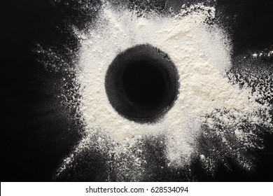 Abstract background. Sprinkled wheat flour circle, round spot on black. Top view on blackboard. Baking concept, cooking dough or pastry.