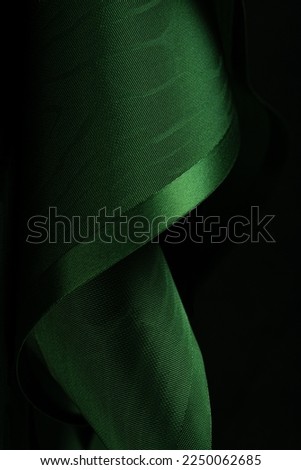 Abstract background. Swirling roll of  green satin fabric.Selective focus.
