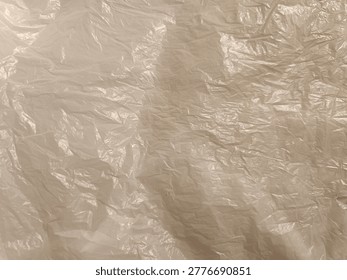 An abstract background texture created by a close-up view of a crumpled white plastic bag. The thin, translucent material exhibits a complex network of wrinkles and creases. The interplay of light and shadow across the off-white surface emphasizes the synthetic, flimsy characteristics of the packaging material.