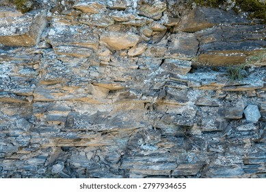 Abstract background texture featuring the complex geometric fractures of a natural stone wall, highlighted by subtle green oxidation and deeply weathered layers.