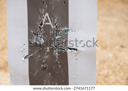Abstract background or texture of a fiberboard surface completely riddled with multiple bullet holes from gunfire or target practice.