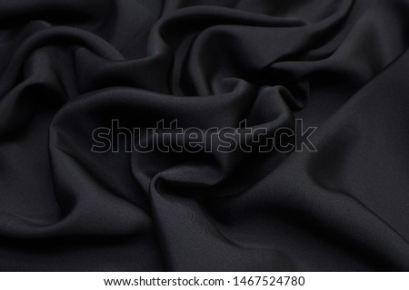 Abstract background texture of natural black color fabric. Fabric texture of natural cotton or linen, silk or satin, wool or jersey textile material. Luxurious dark gray canvas background.
