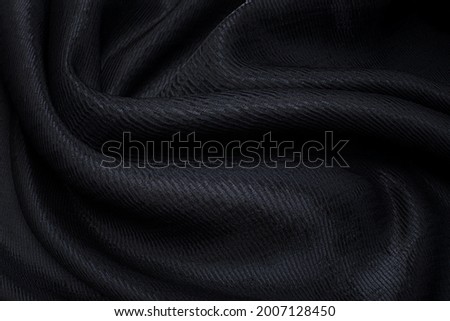 Abstract background texture of natural black color fabric. Fabric texture of natural cotton or linen, silk or satin, wool or jersey textile material. Luxurious dark gray canvas background.
