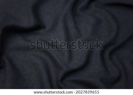 Abstract background texture of natural black color fabric. Fabric texture of natural cotton or linen, silk or satin, wool or jersey textile material. Luxurious dark gray canvas background.
