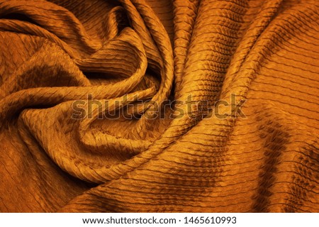 Abstract background texture of natural orange or golden colour fabric. Fabric texture of natural cotton or linen, silk or satin, wool or jersey textile material. Luxurious canvas background.
