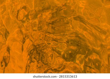 Abstract background texture of transparent fluid pool water illuminated with warm orange light showing wavy ripples and sun reflections for vivid creative design.