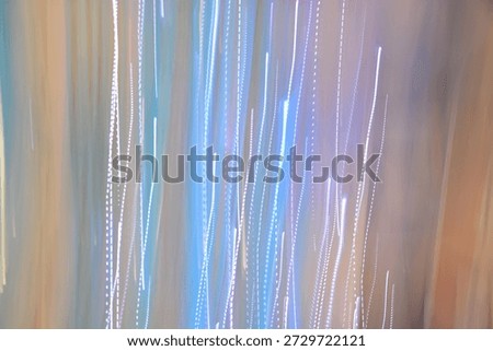 Abstract background with vertical light trails and motion blur effect in soft blue, white, and beige pastel tones.