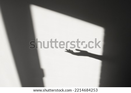 Abstract background with window shadow and geometric lines on a gray wall. Reflection of a human hand, a template with a gesture.