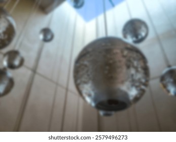 Abstract background without focus, lighting installation in the form of transparent glass balls hanging from the ceiling, creating an aesthetic and modern effect.