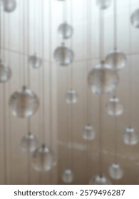 Abstract background without focus, lighting installation in the form of transparent glass balls hanging from the ceiling, creating an aesthetic and modern effect.