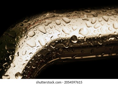 Abstract background. Yellow metal pipe covered water droplets. Raindrops on bend of metal pipe isolated on black. Shiny water droplets on surface of metal. Rain water drop on stainless rail.