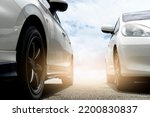 Abstract of beside of two cars on the asphalt road. Park the car outdoors next to each other. Or parpare for the race. with background outdoor of blue sky and white clouds with sunlight.